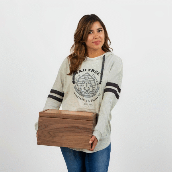 Woman wearing a light gray Mad Tree Woodcrafts & Engraving hoodie, holding a handcrafted walnut keepsake box against a white background.