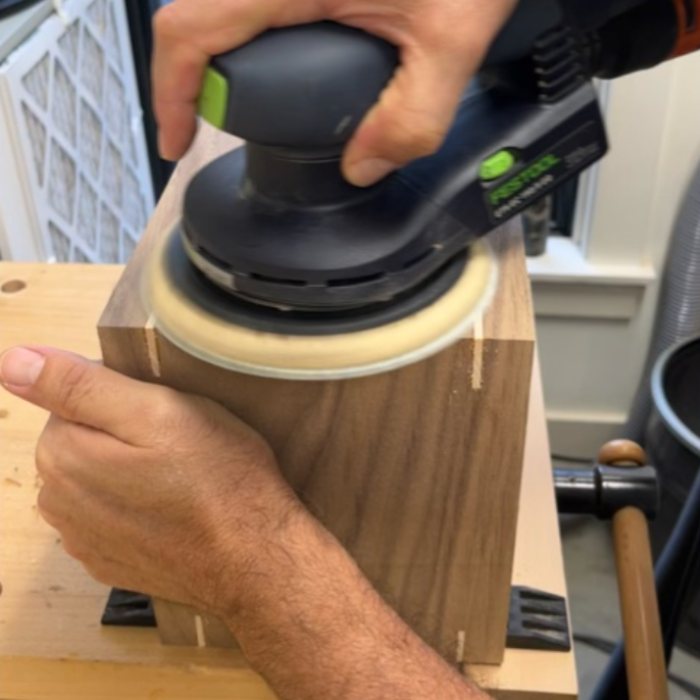 Smoothing the box surface by hand sanding with an orbital sander before final assembly