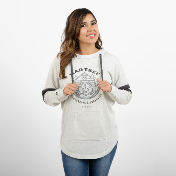 Woman smiling and looking to the side while wearing a light gray Mad Tree Woodcrafts & Engraving hoodie with a front pouch pocket and dark gray drawstrings.