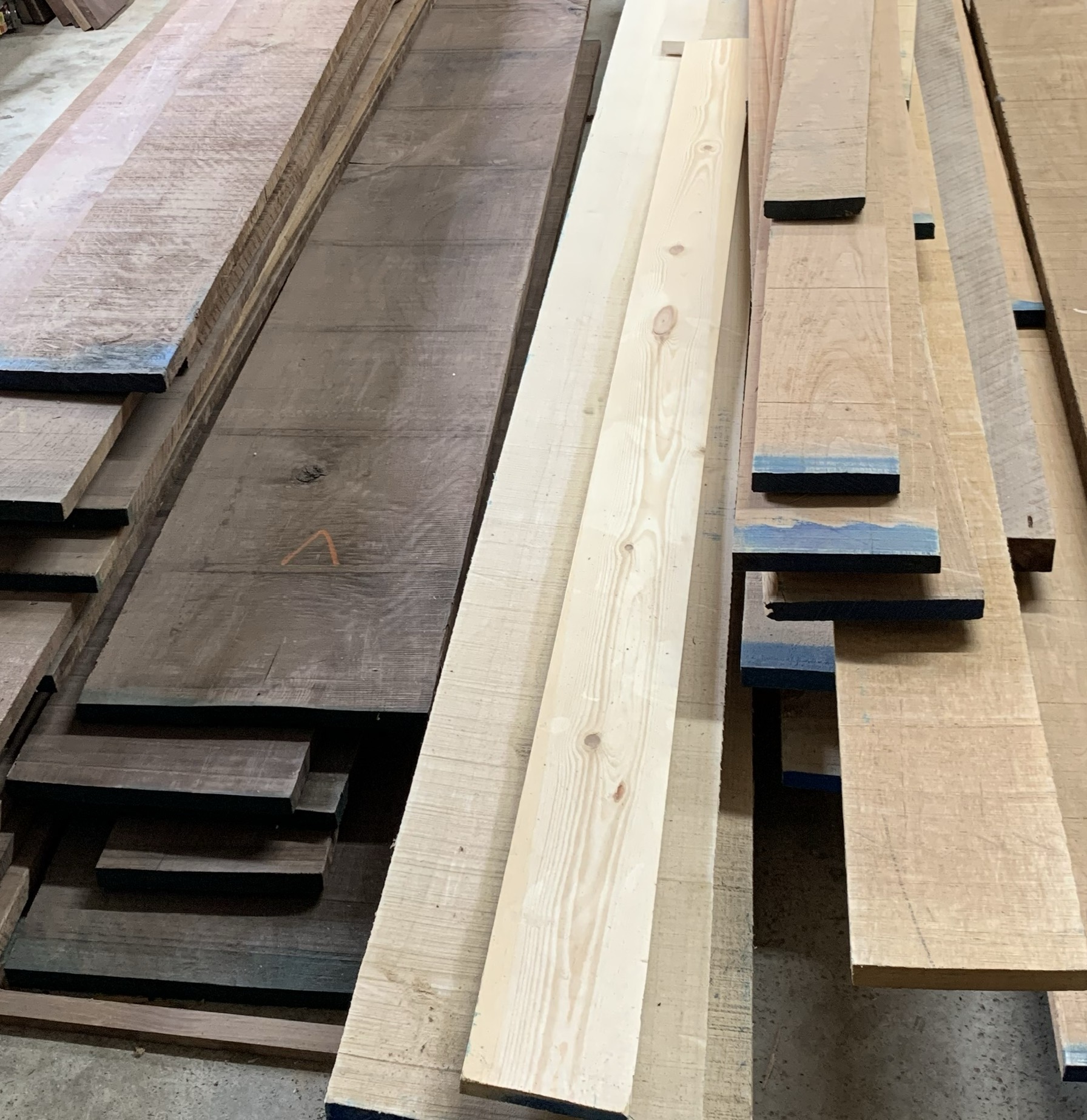 Stacks of raw hardwood lumber in the Mad Tree Woodcrafts workshop, ready for custom boxes.