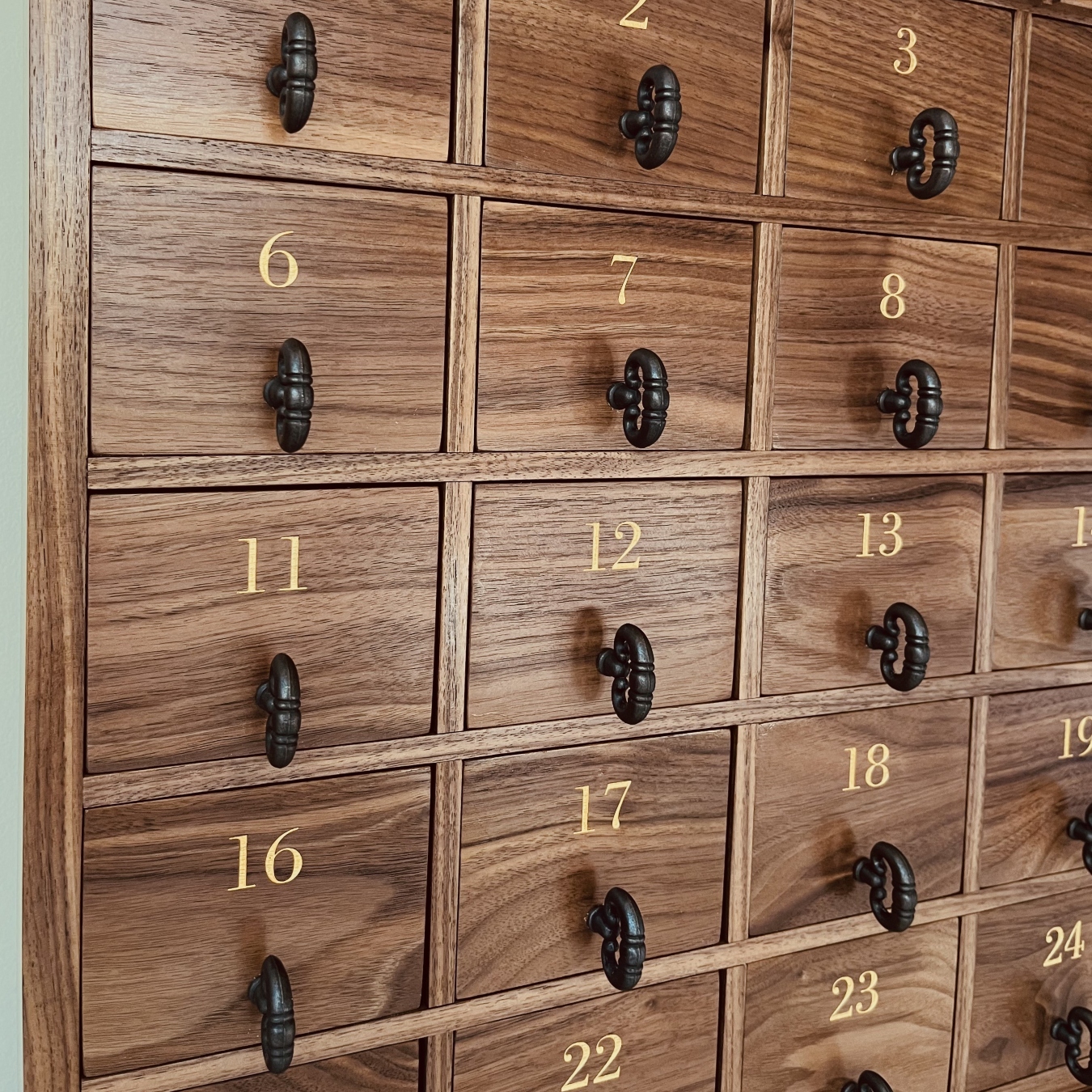 Detailed view of walnut grain, numbered drawers, and hardware on a handcrafted advent calendar